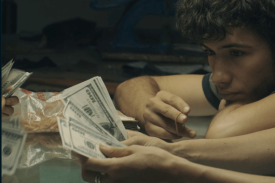 still from Cambio, Cambio; young man watches money being counted